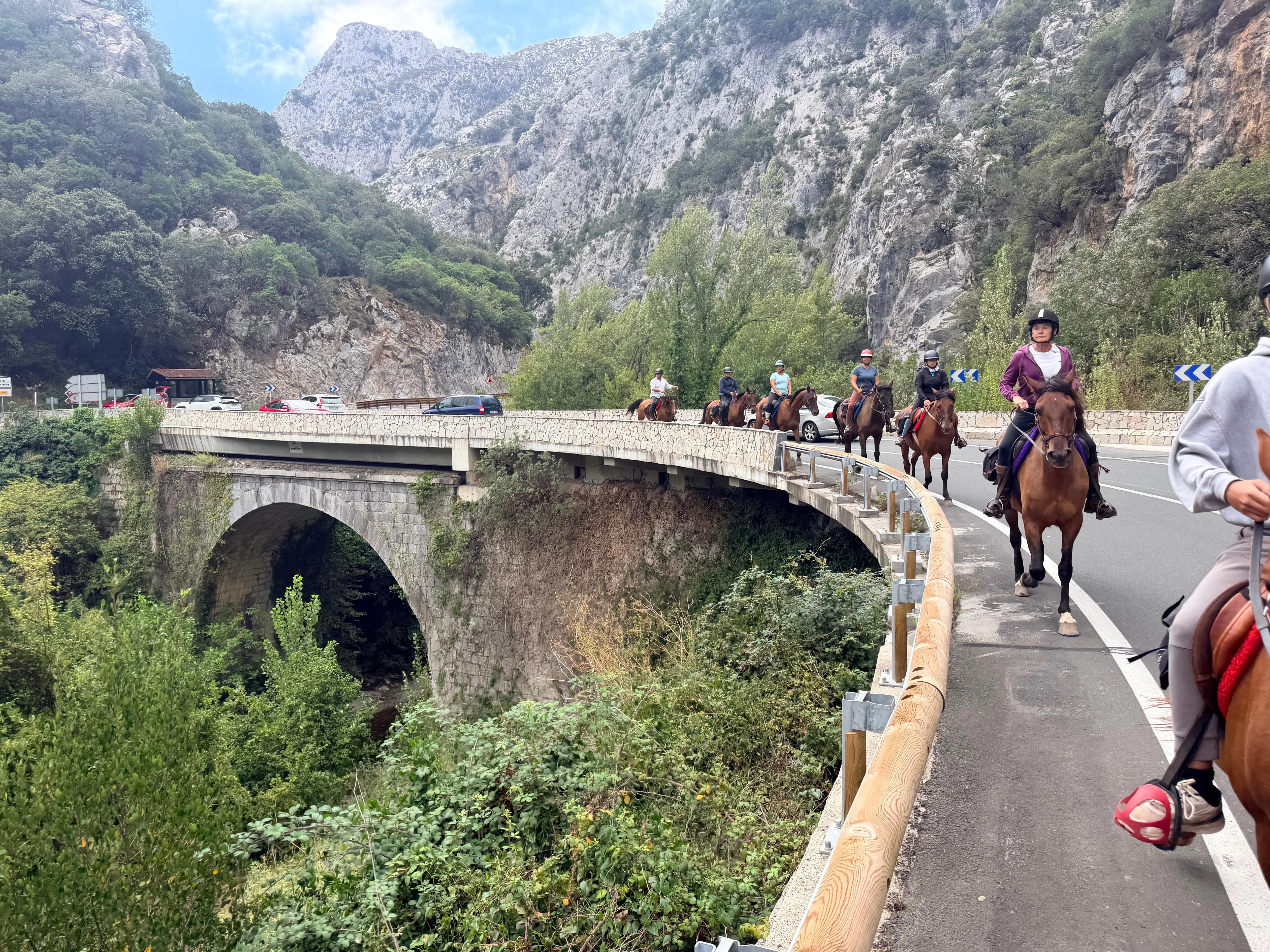 Jinetes cruzando el puente de piedra en el Camino Lebaniego